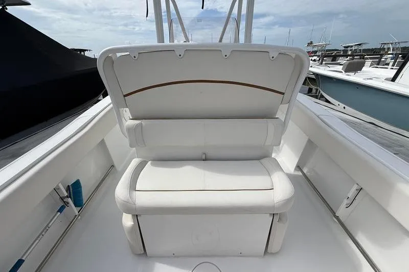 Slide: The Image of 2022 Sea Hunt Ultra 234 boat interior with white cushioned seating at marina. - 7