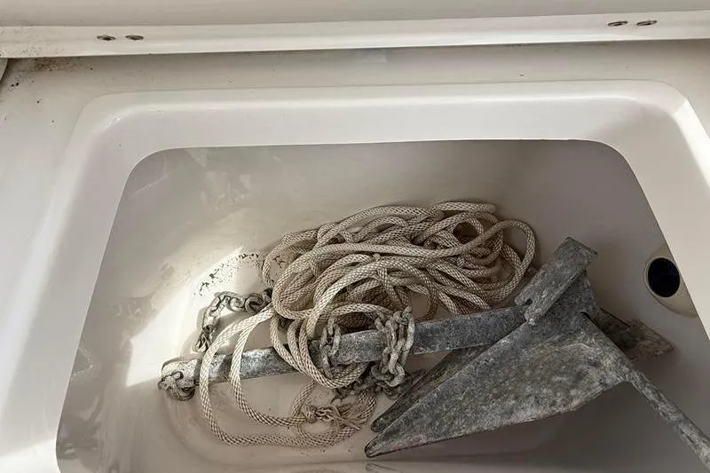 Slide: The Image of Anchor and rope stored in a compartment of a 2022 Sea Hunt Ultra 234 boat. - 5