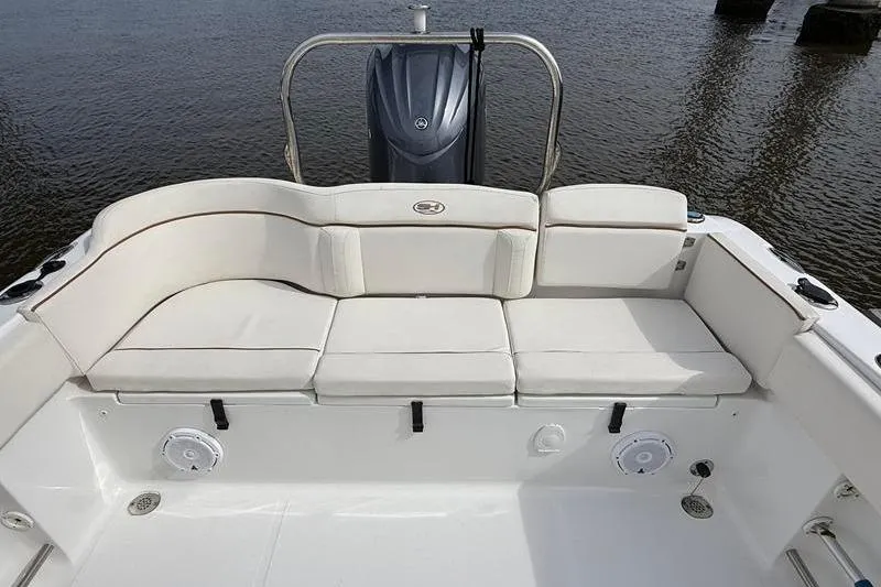 Slide: The Image of 2022 Sea Hunt Ultra 234 boat with cushioned seating and outboard motor, on calm water. - 3