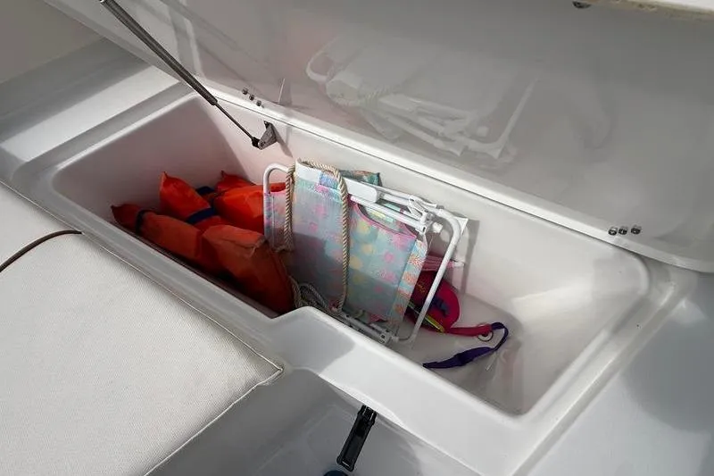 Slide: The Image of Storage compartment on 2022 Sea Hunt Ultra 234 boat with life jackets and beach chairs. - 25