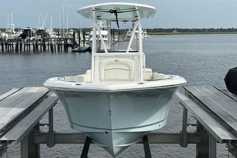 Slide: The Image of 2022 Sea Hunt Ultra 234 boat docked at a marina with other vessels in the background. - 1