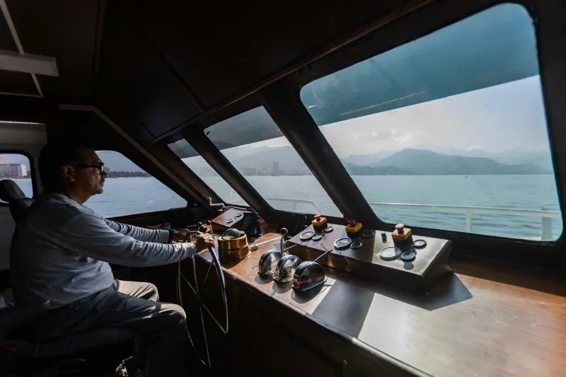 Slide: The Image of A man navigates a passenger ferry with views of the sea and mountains. - 6