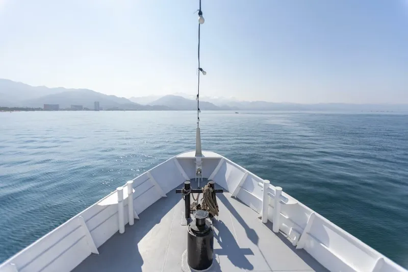 Slide: The Image of A passenger ferry with a white deck sails on calm waters, surrounded by mountains in the background. - 7