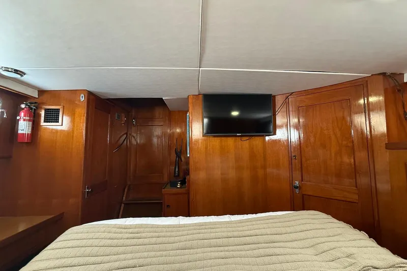 Slide: The Image of 1985 DeFever 40 Offshore Cruiser cabin with wood paneling, TV, and fire extinguisher. - 24