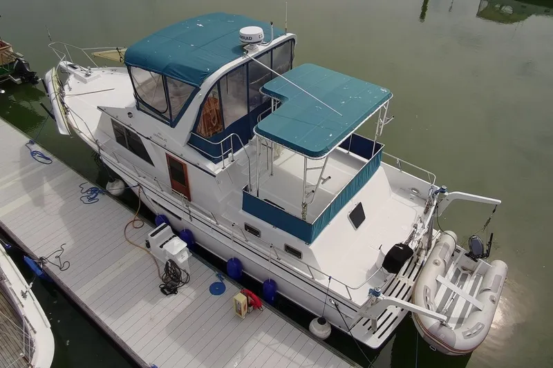 Slide: The Image of 1985 DeFever 40 Offshore Cruiser docked, featuring blue canopy and inflatable dinghy. - 2