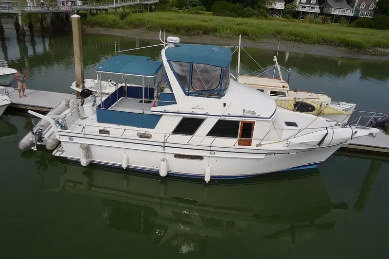 Slide: The Image of 1985 DeFever 40 Offshore Cruiser docked in a serene marina setting. - 7