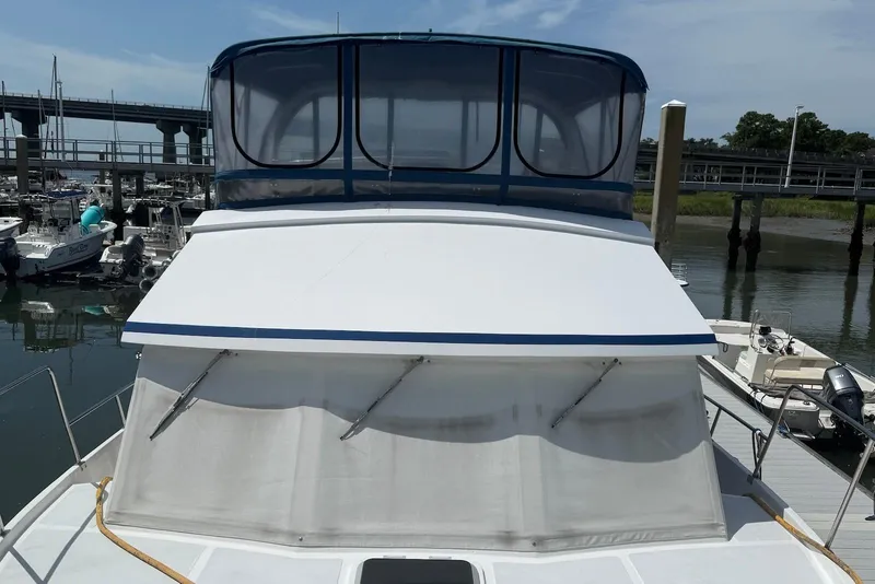 Slide: The Image of 1985 DeFever 40 Offshore Cruiser docked at marina, featuring blue canopy and white deck. - 22