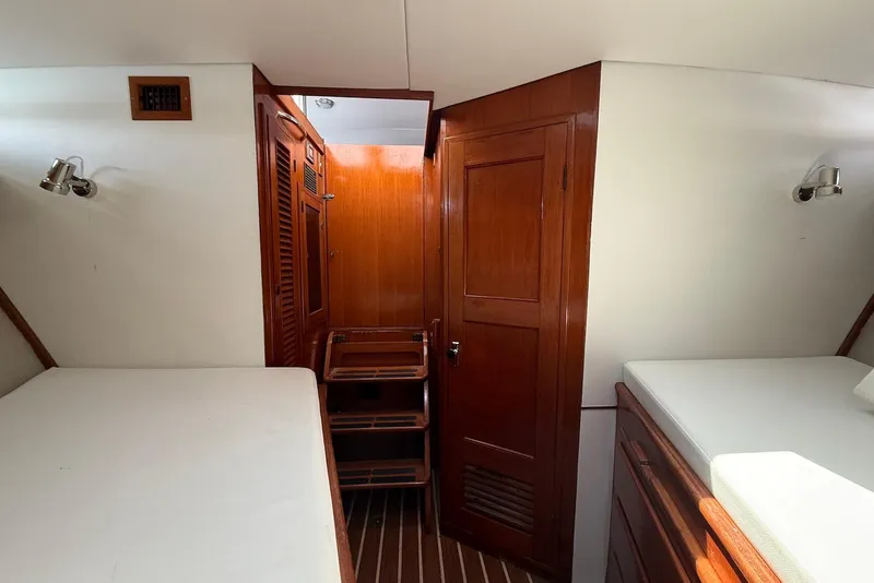 Slide: The Image of Interior of 1985 DeFever 40 Offshore Cruiser with wooden cabinetry and white bedding. - 42