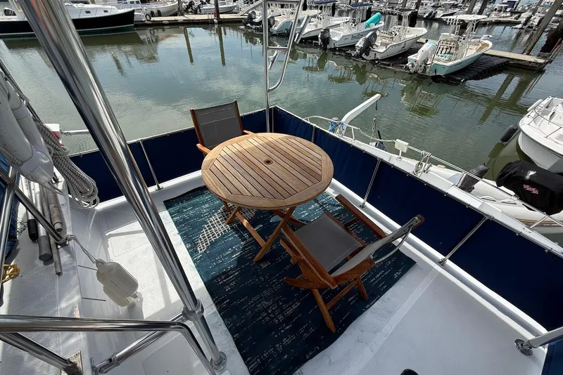 Slide: The Image of 1985 DeFever 40 Offshore Cruiser deck with wooden table and chairs, overlooking marina. - 11