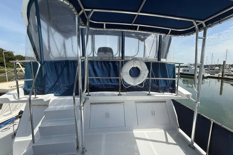 Slide: The Image of 1985 DeFever 40 Offshore Cruiser with blue canopy and life preserver, docked at marina. - 20
