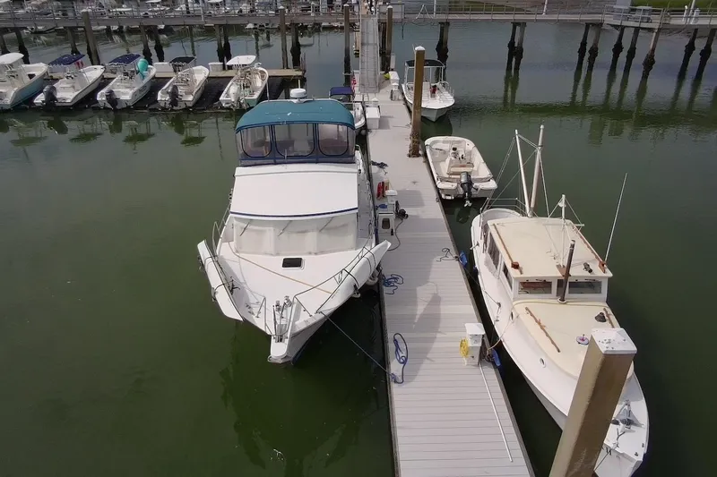 Slide: The Image of 1985 DeFever 40 Offshore Cruiser docked at marina, surrounded by smaller boats. - 5
