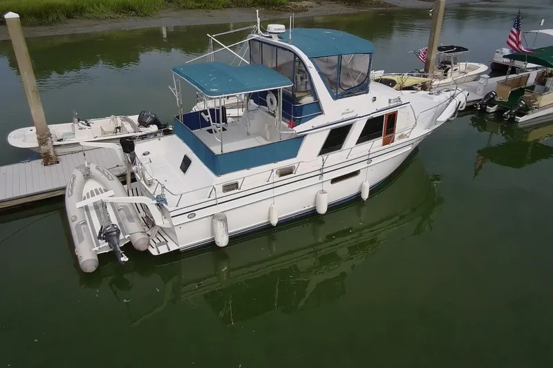 Slide: The Image of 1985 DeFever 40 Offshore Cruiser docked, featuring a blue canopy and inflatable dinghy. - 6