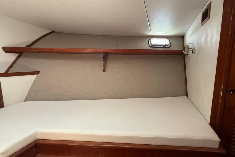 Slide: The Image of 1985 DeFever 40 Offshore Cruiser cabin interior with bed and wooden shelf. - 40