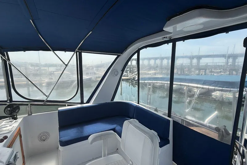 Slide: The Image of Interior view of 1985 DeFever 40 Offshore Cruiser with blue seating and marina backdrop. - 18