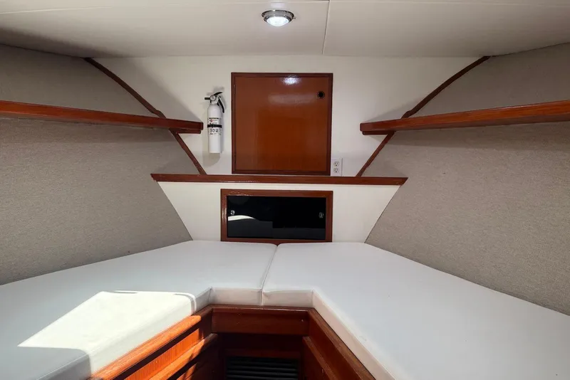 Slide: The Image of 1985 DeFever 40 Offshore Cruiser cabin interior with white cushions and wooden shelves. - 38