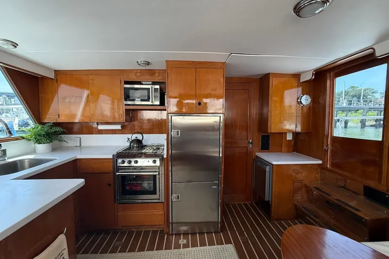 Slide: The Image of 1985 DeFever 40 Offshore Cruiser kitchen with wood cabinetry, stainless appliances, and large windows. - 32