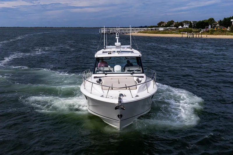 Slide: The Image of 2024 Boston Whaler 405 Conquest cruising on open water near a coastal shoreline. - 4