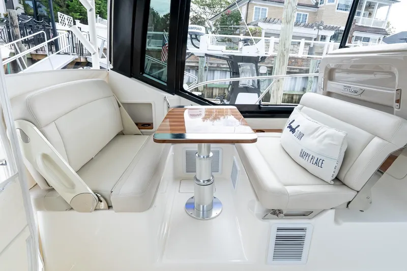 Slide: The Image of 2024 Boston Whaler 405 Conquest interior with plush seating and wooden table. - 34