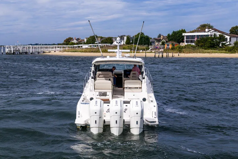 Slide: The Image of 2024 Boston Whaler 405 Conquest cruising near a scenic shoreline. - 7