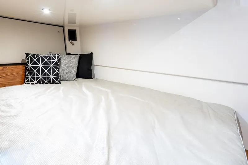 Slide: The Image of 2024 Boston Whaler 405 Conquest cabin interior with cozy bed and decorative pillows. - 58