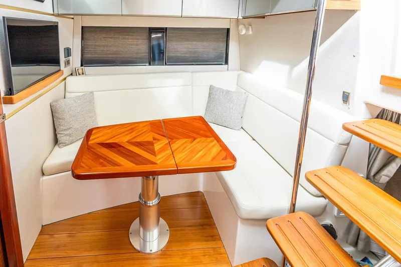 Slide: The Image of 2024 Boston Whaler 405 Conquest interior with elegant wood table and white seating. - 49