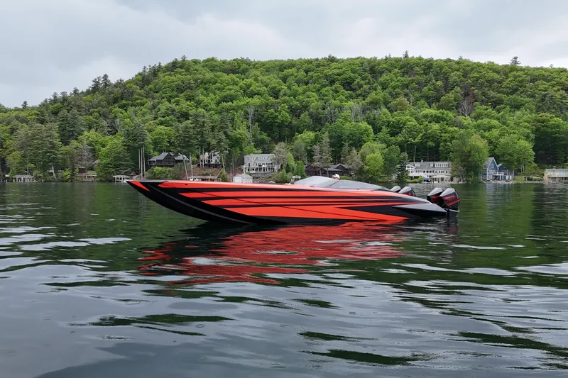 Slide: The Image of 2027 Nor-Tech 4000 Roadster boat on a serene lake with lush green hills. - 3