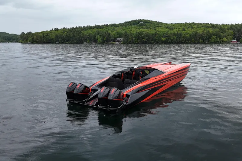 Slide: The Image of 2027 Nor-Tech 4000 Roadster boat on a serene lake with lush green shoreline. - 1