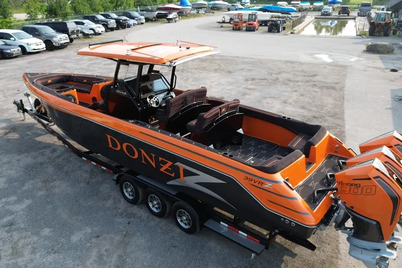 Slide: The Image of 2024 Donzi 39 VRZ boat with vibrant orange and black design, parked on a trailer. - 65