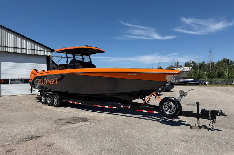 Slide: The Image of 2024 Donzi 39 VRZ boat on trailer, vibrant orange and black design, parked outdoors. - 16