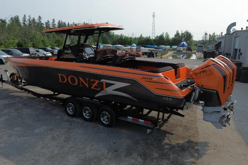 Slide: The Image of 2024 Donzi 39 VRZ boat with triple outboard engines on a trailer, parked outdoors. - 64