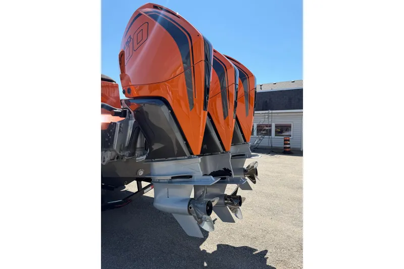 Slide: The Image of 2024 Donzi 39 VRZ boat with triple orange outboard engines, parked outdoors. - 10