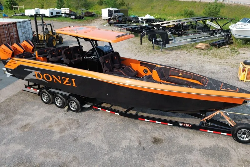 Slide: The Image of 2024 Donzi 39 VRZ powerboat with vibrant orange and black design on a trailer. - 57
