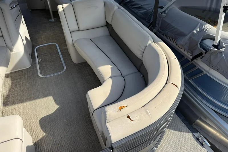 Slide: The Image of 2016 Bennington 2550 RBR boat interior with worn beige seating and carpeted floor. - 13