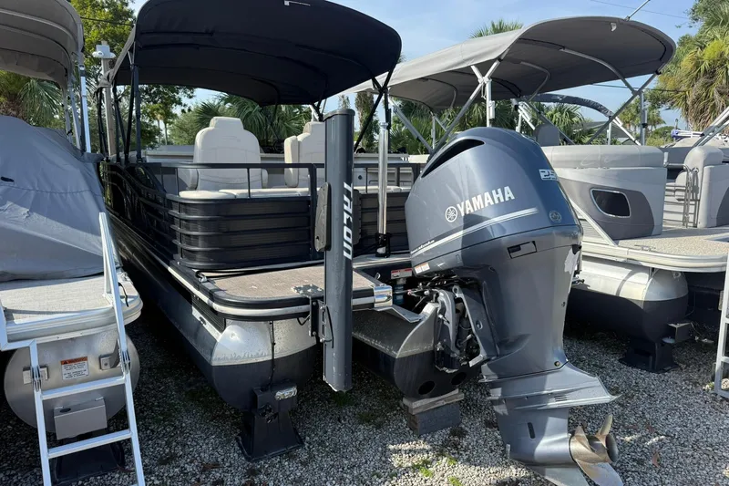 The Image of 2016 Bennington 2550 RBR pontoon boat with Yamaha outboard motor, parked on gravel. - 0