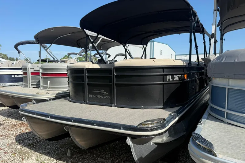 Slide: The Image of 2016 Bennington 2550 RBR pontoon boat with canopy, docked alongside similar vessels. - 16