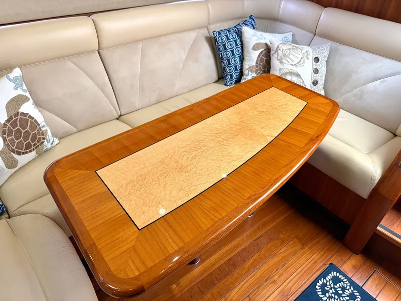 Slide: The Image of Elegant salon area with a polished wood table and comfortable seating, decorated with nautical-themed pillows. - 39