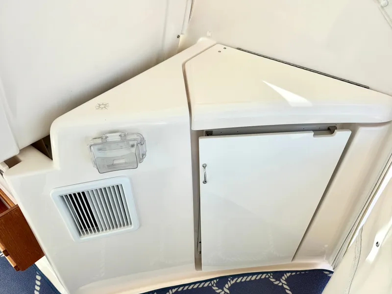 Slide: The Image of A white cabinet with a door and a vent on a boat. - 24