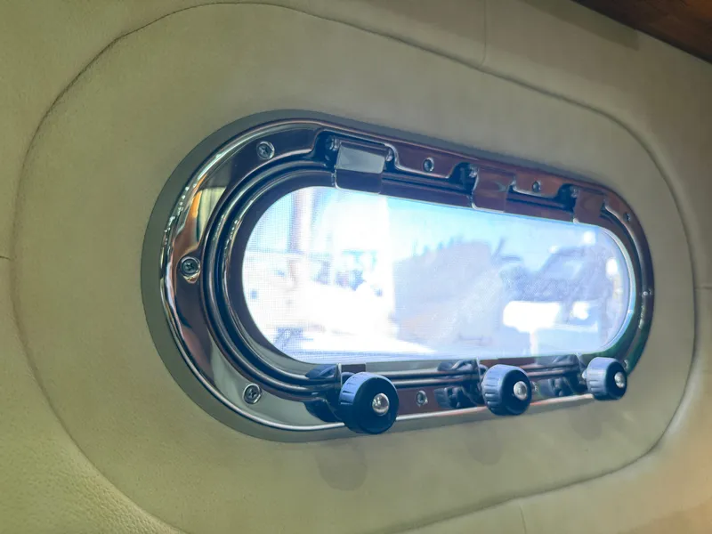 Slide: The Image of An oval porthole with a polished metal frame and three latches, set in a padded wall. - 45