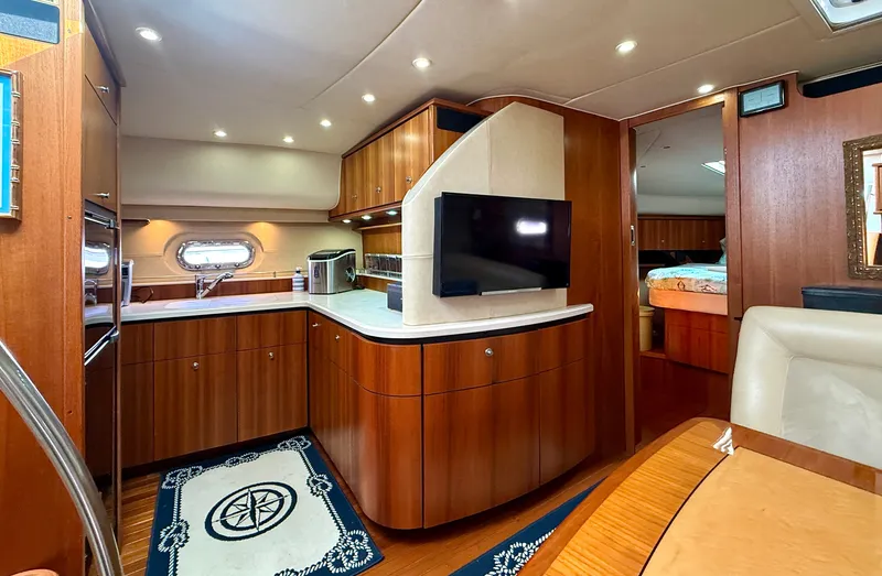 Slide: The Image of The interior of a 2006 Tiara Yachts 4300 Sovran features an elegant wood-paneled kitchen and a TV. - 42