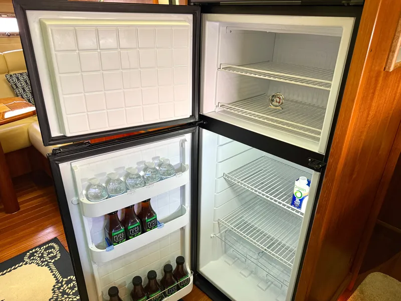 Slide: The Image of An open fridge on a yacht displays water bottles and drinks. Interior features wooden flooring. - 47