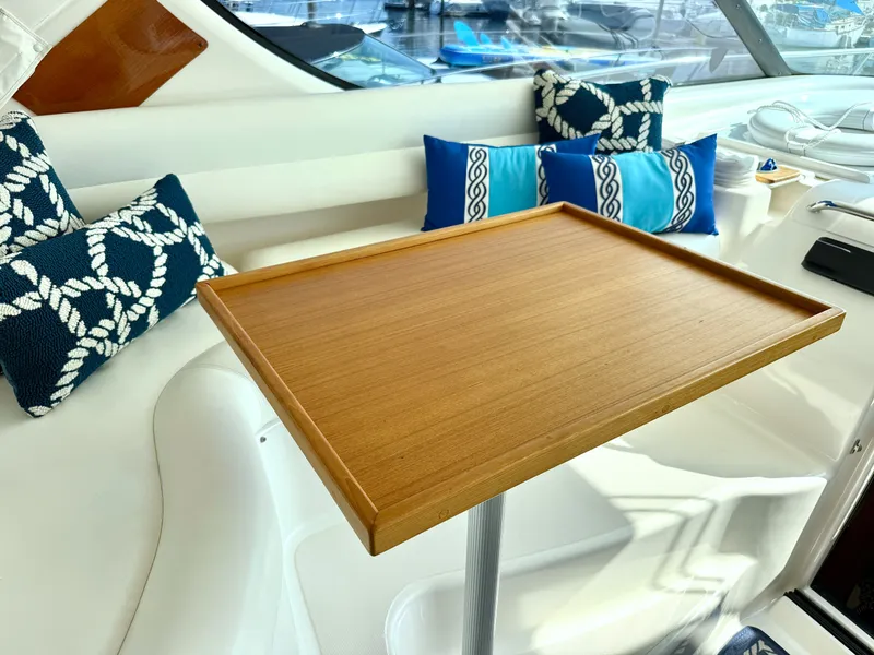Slide: The Image of A sleek wooden table on a yacht, surrounded by blue cushions with nautical designs. - 27