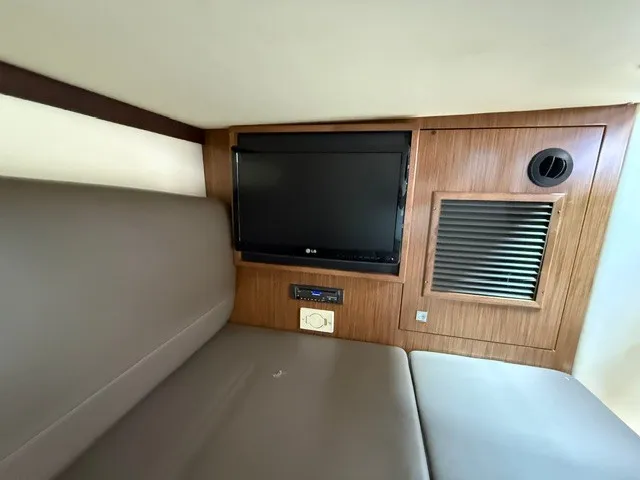 Slide: The Image of The interior of a 2013 Cruisers Yachts 380 Express features a cozy seating area with a TV. - 17