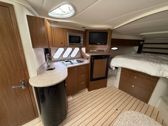 Slide: The Image of Interior of a 2013 Cruisers Yachts 380 Express with wood cabinetry, kitchenette, and sleeping area. - 15