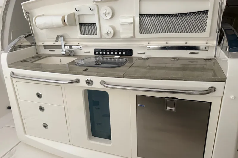 Slide: The Image of 2024 Boston Whaler 420 Outrage boat kitchen with sink, storage, and stainless steel fridge. - 20