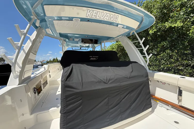 Slide: The Image of 2024 Boston Whaler 420 Outrage boat interior with covered seating and blue canopy. - 8