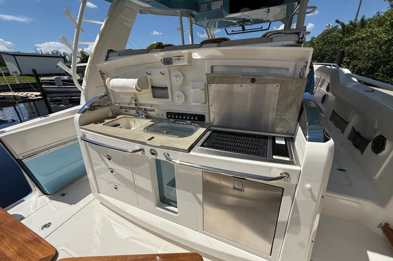 Slide: The Image of 2024 Boston Whaler 420 Outrage boat kitchen with grill, sink, and storage. - 60