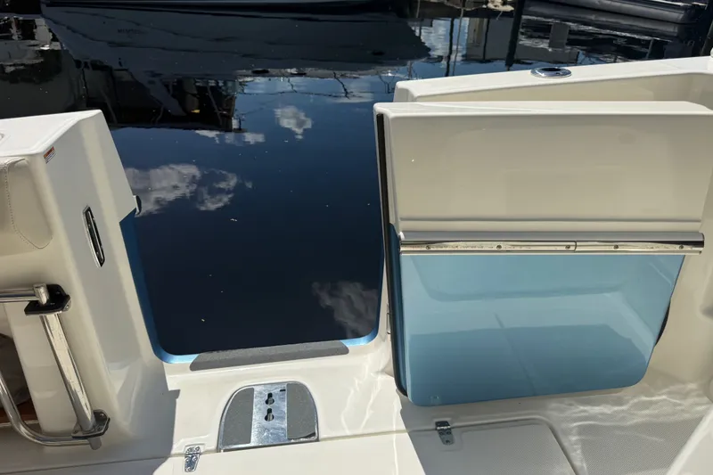 Slide: The Image of 2024 Boston Whaler 420 Outrage boat with open transom door, reflecting sky and water. - 61