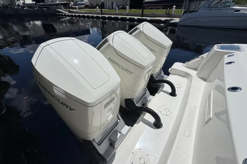 Slide: The Image of Triple Mercury engines on a 2024 Boston Whaler 420 Outrage, docked in a marina. - 85