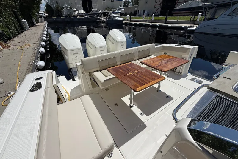 Slide: The Image of 2024 Boston Whaler 420 Outrage boat with luxurious seating and wooden tables docked at marina. - 62