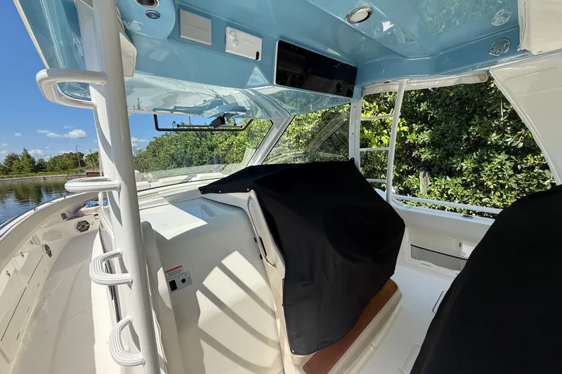 Slide: The Image of 2024 Boston Whaler 420 Outrage interior, showcasing helm area with protective covers and sleek design. - 37